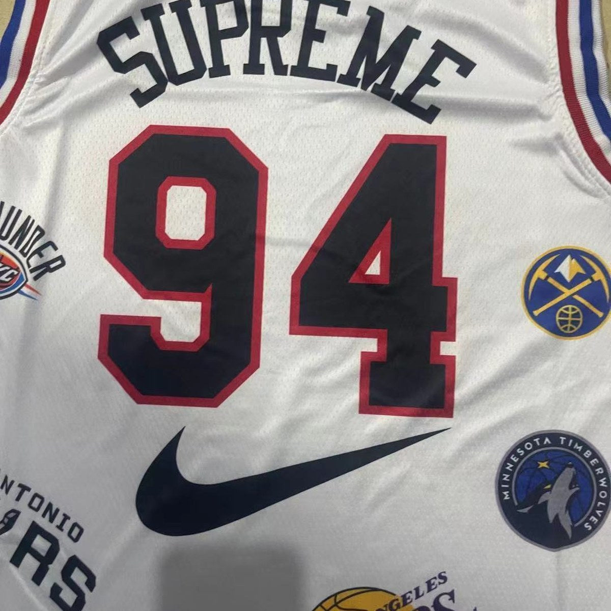 גופיית כדורסל בעיצוב NBA ו־Supreme מספר 94 לבן (תקריב של הבד וההדפס)
